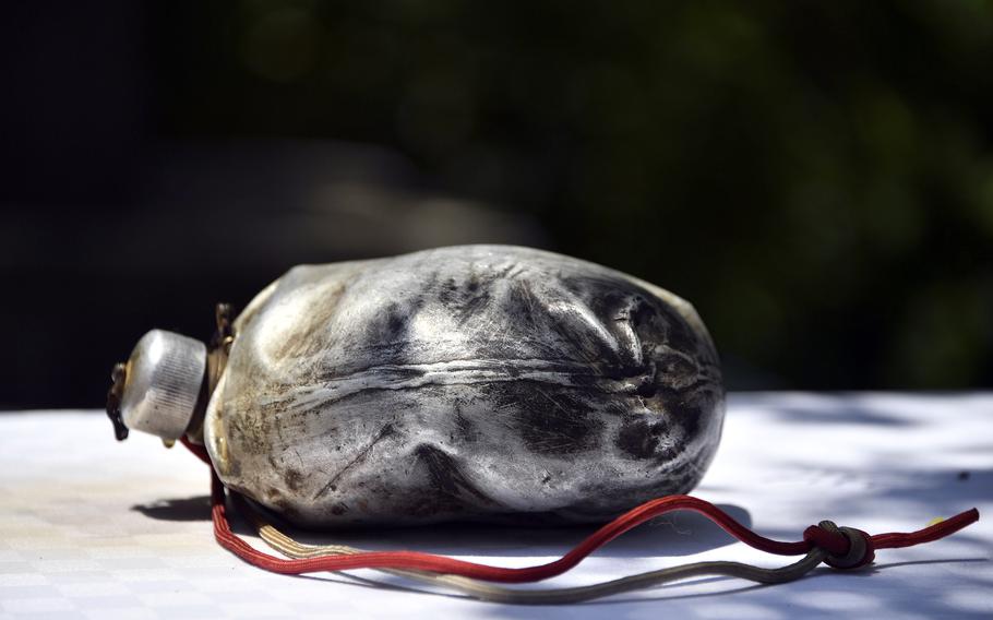 A blackened canteen bearing the fingerprints of a U.S. airman is displayed.