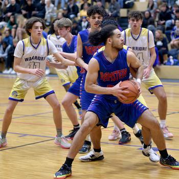 Ramstein's israel Rouse backs down a defender during a game at Wiesbaden High School on Thursday in Wiesbaden, Germany. In the background are the Warriors' Gavin DeLuca, left, and Collin Koschnik, right.