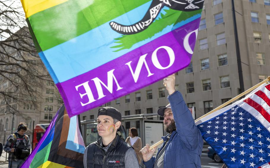 Two people standing and surrounded by flags.