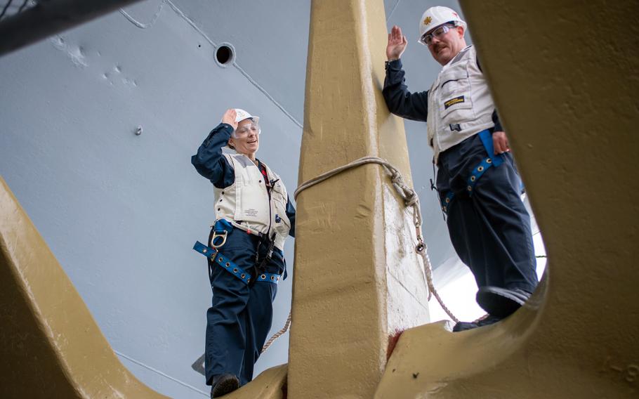 Command Senior Chief Petty Officer Brianna Ridlon, left, reenlists in the Navy standing atop one of the USS Ronald Reagan's anchors at Yokosuka Naval Base, Japan, April 1, 2024. 