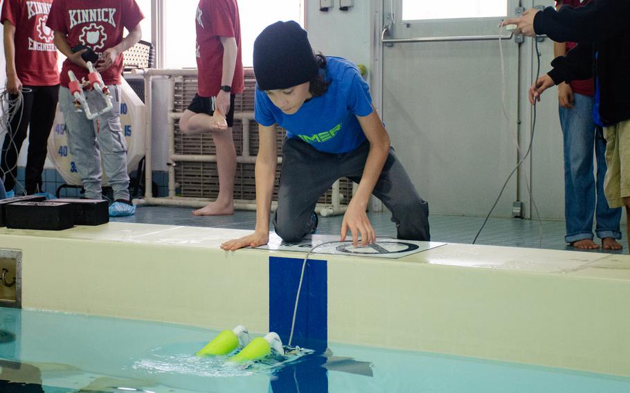 SeaPerch Challenge competitor Rafael Menzel places his team's remotely-operated vehicle into the aquatic obstacle course at Yokosuka Naval Base, Japan, on April 7, 2024.