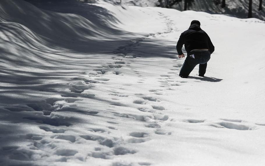 A volunteer postholes through deep snow as he checks on area residents in the San Bernardino Mountain community on March 7, 2023, in Crestline, Calif.