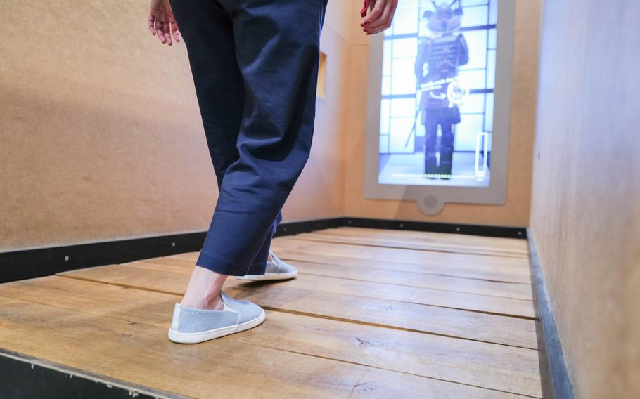 A visitor tries to sneak past a computer-screen samurai by stepping carefully on sound-sensitive floorboards at the ninja obstacle course in the Experimenta Science Center.