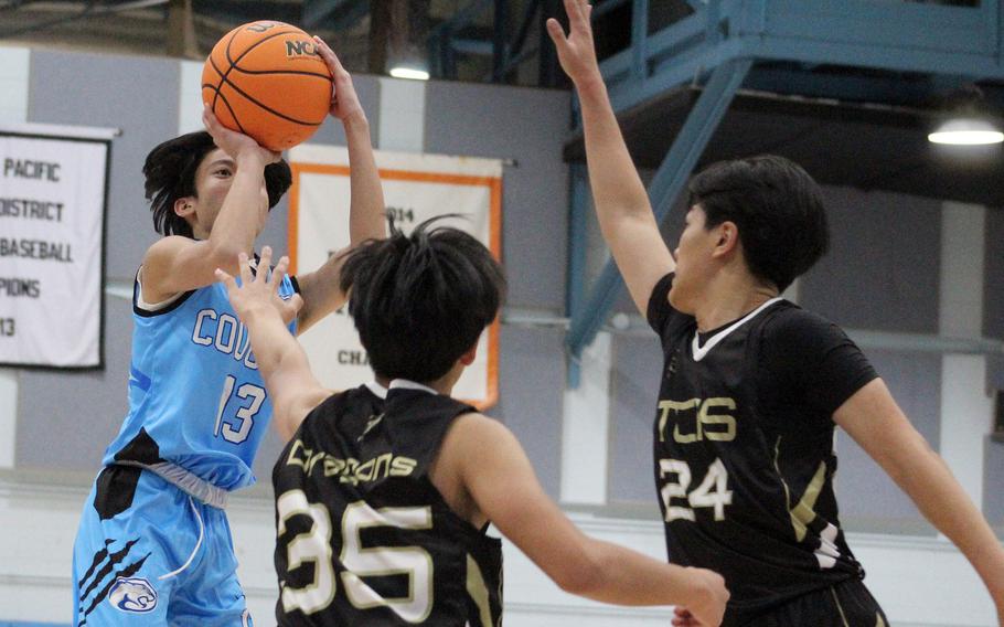 Osan's R.J. Jones shoots against Taejon Christian's David Chung and Justin Soung during Friday's Korea boys basketball game. The Cougars won 52-31.