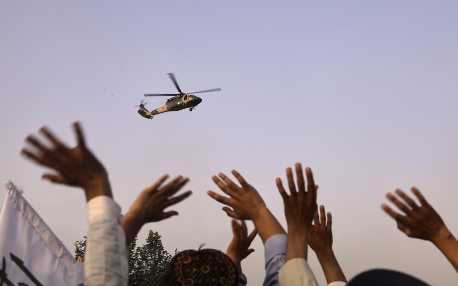 Hands take up the bottom third of the image, while the rest of the image consists of a clear sky and a single helicopter.