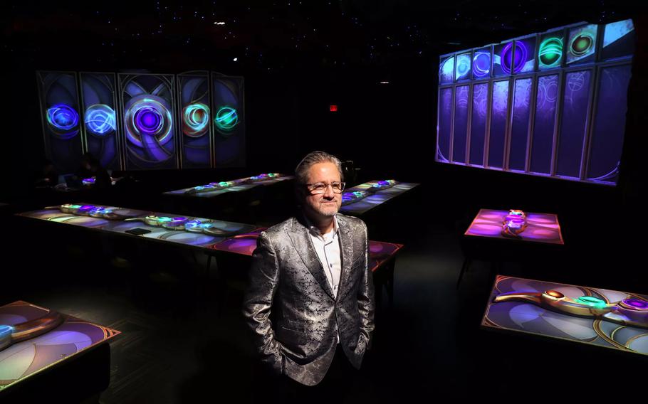 The Gallery co-founder Daren Ulmer stands among tables illuminated by projectors at his new downtown LA restaurant.