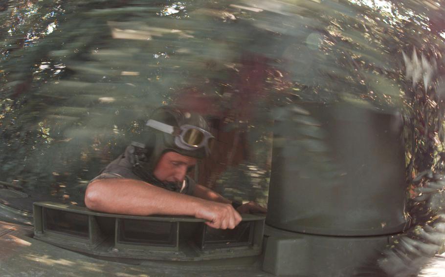 A soldier ducks under branches.