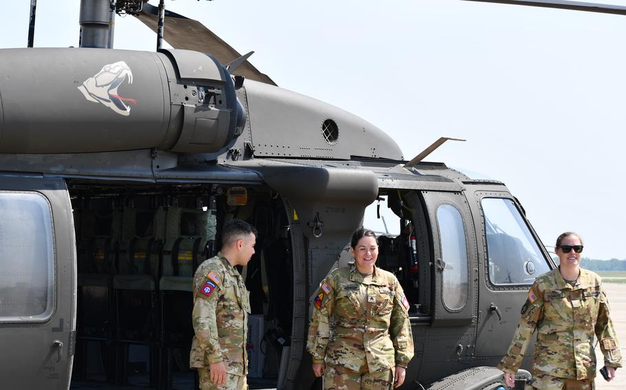 Three soldiers stand in front of a UH-60 helicopter.
