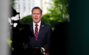 Michael Waltz seen speaking past the shoulders of journalists and their cameras.