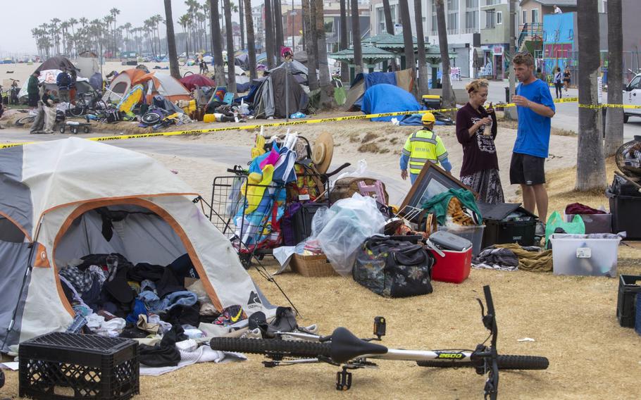 A couple experiencing homelessness waits for outreach workers at an encampment in the Venice Beach area of Los Angeles on July 2, 2021.