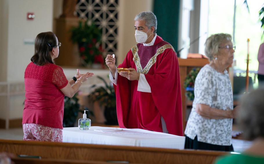 Monsignor Edward Filardi of St. Paul Catholic Church in Damascus, Md., leads a Saturday service. He sanitized his hands and put a mask on before giving Holy Communion in front of tables with sanitizer. 