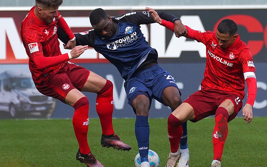 Two FC Kaiserlautern players  fighting for the soccer ball against a Paderborn player.