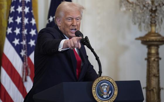 President Trump speaks into a microphone and points one finger out.