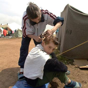 An ethnic Albanian refugee gets his hair cut as part of a somewhat normal lifestyle at Brazda refugee camp in Macedonia, May 8, 1999. Brazda was the biggest camp in Macedonia holding more than 30,000 refugees.