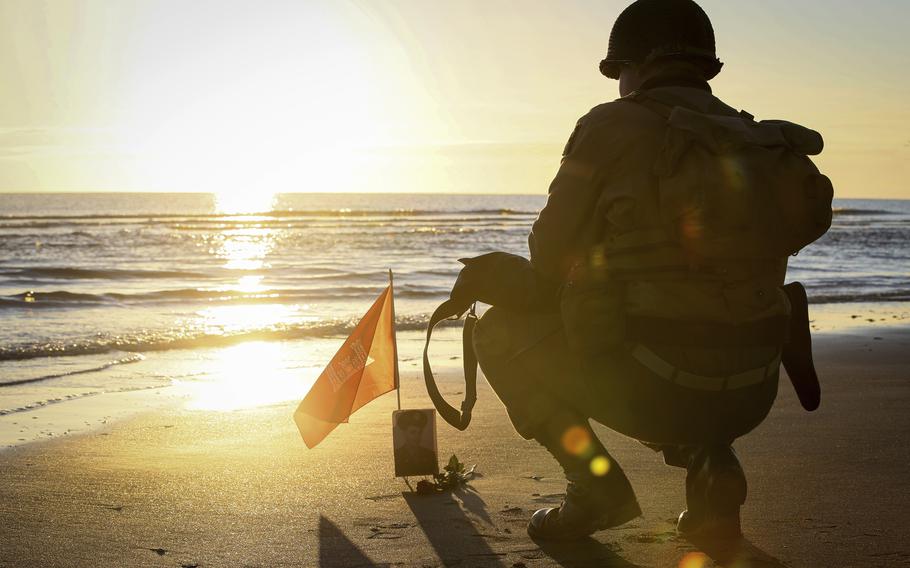 A World War II reenactor pays tribute to a soldier on Omaha Beach in Saint-Laurent-sur-Mer, Normandy, Sunday, June 6, 2021, the day of 77th anniversary of the assault that helped bring an end to World War II. 