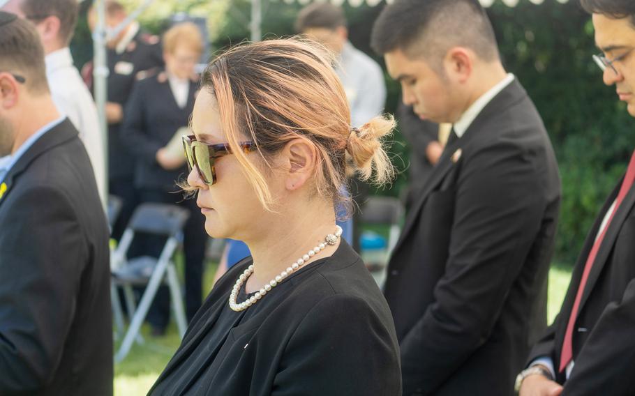 People dressed in black bow their heads during a memorial service.