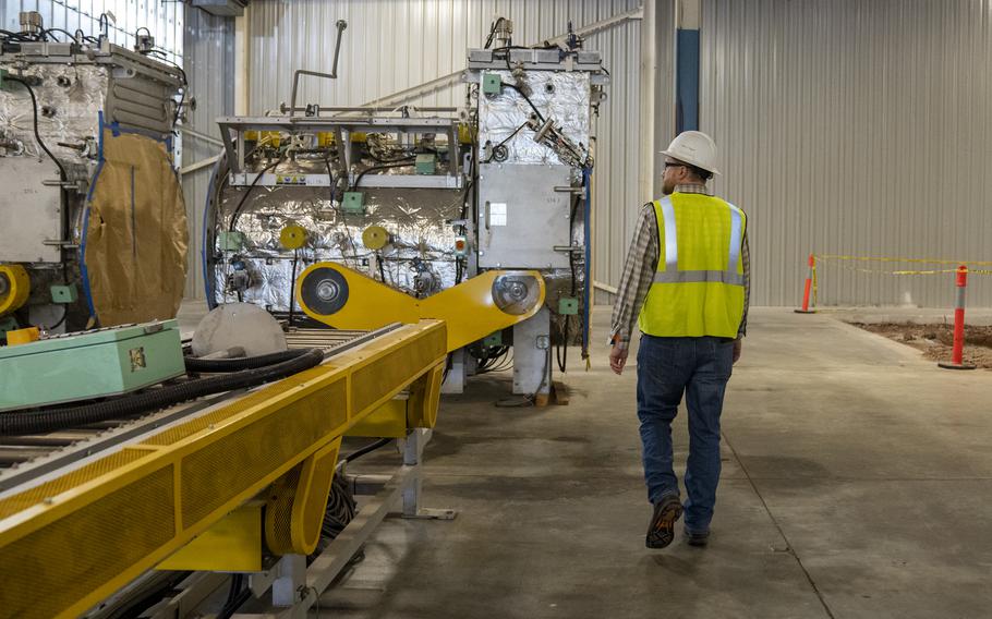 A worker walks past conveyor belt at a factory.