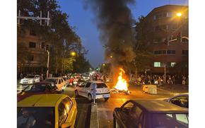In this Sept. 19, 2022, photo taken by an individual not employed by the Associated Press and obtained by the AP outside Iran, a police motorcycle burns during a protest over the death of a young woman who had been detained for violating the country's conservative dress code, in downtown Tehran, Iran. 