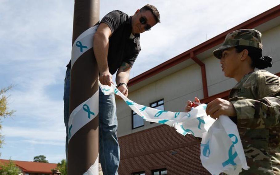 Staff Sgt. Taylor Pruss, victim advocate for the 603 Aviation Support Battalion, 3rd Combat Aviation Brigade, 3rd Infantry Division, and 1st Lt. Aniko Austin, victim advocate for Headquarters and Headquarters Company, 3rd CAB, 3rd ID, set up displays for Sexual Assault Awareness and Prevention Month at Hunter Army Airfield, Ga., on April 1, 2022. 