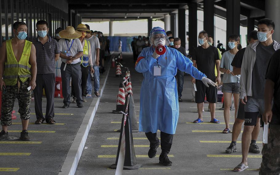 A volunteer in protective gears uses a loud speaker to advise people to keep social distancing at a COVID-19 testing site in Sanya in south China’s Hainan Province on Aug. 7, 2022. 