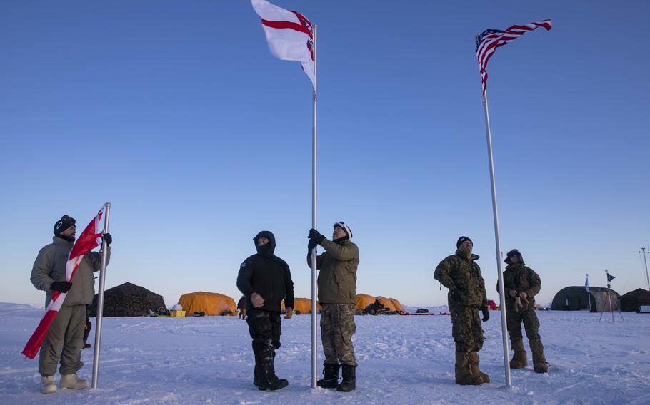 U.S. sailors and Marines and counterparts from Canada and the U.K. raise flags at Ice Camp Queenfish in the Beaufort Sea on March 4, 2022.