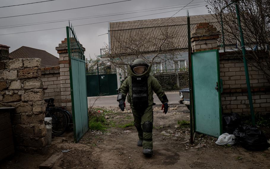 A senior deminer with Ukraine’s State Emergency Service arrives at a home in Mykolaiv where an unexploded cluster munition waits in the garden. 