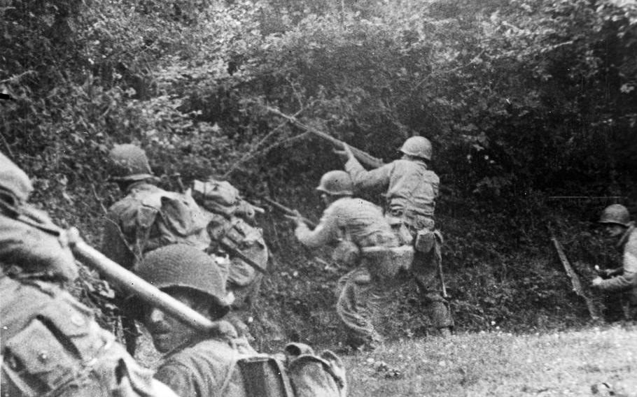 U.S. infantrymen drop into a ditch by the side of a field and prepare to shoot a rifle grenade at a German sniper who has suddenly fired on them, somewhere in the battle area in Normandy.