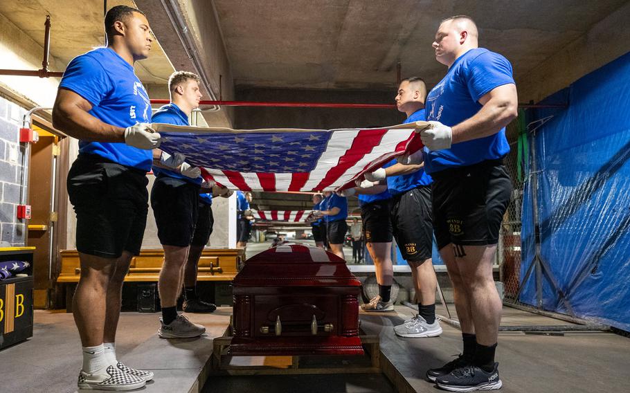 Marines spread out the American flag over a coffin