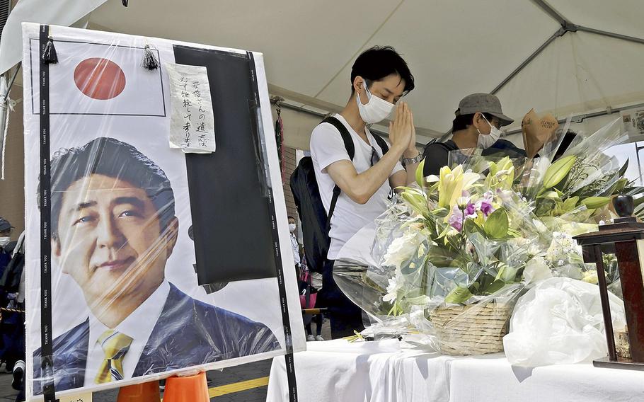 People offer prayers in Nara City in July at a floral tribute stand set up near the site of the fatal attack on former Prime Minister Shinzo Abe. 