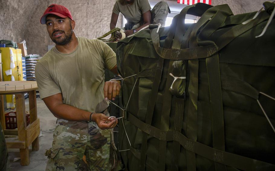 Army Sgt. Robert Alvarado of the 165th Quartermaster Company prepares a bundle of humanitarian aid at Al Udeid Air Base in Qatar on March 16,2024, by inspecting the parachutes attached to each pallet.