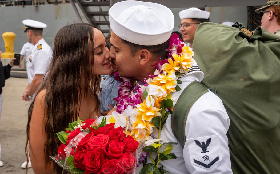A sailor moves in to kiss a woman.