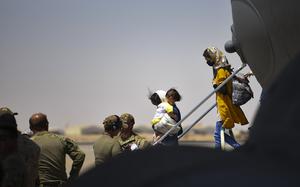 Afghan evacuees exit an airplane.