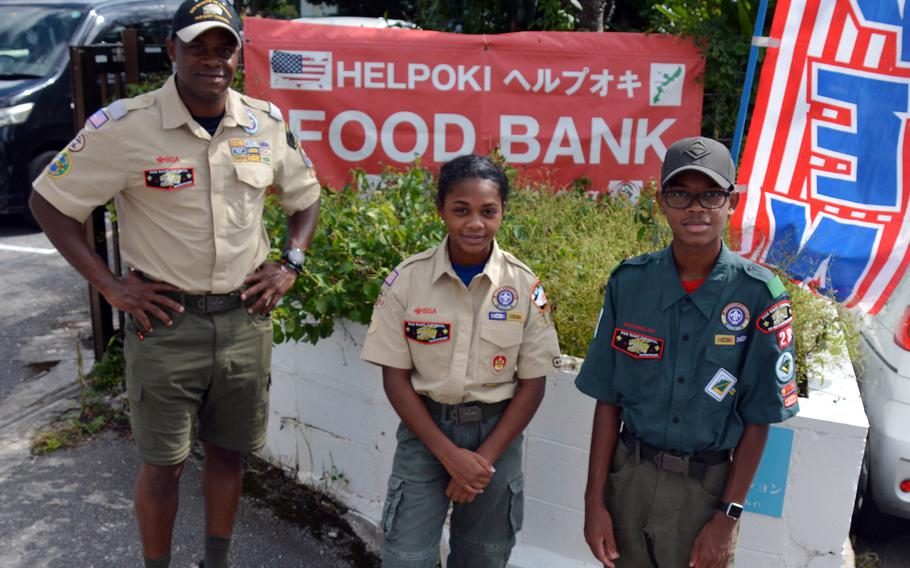 Eagle Scout hopefuls Leila and Nijrell Jackson pose outside the Help Oki community center with their father, Gunnery Sgt. Earl Jackson, a district chairman, adviser and a leader for Scouts ages 14 to 21.