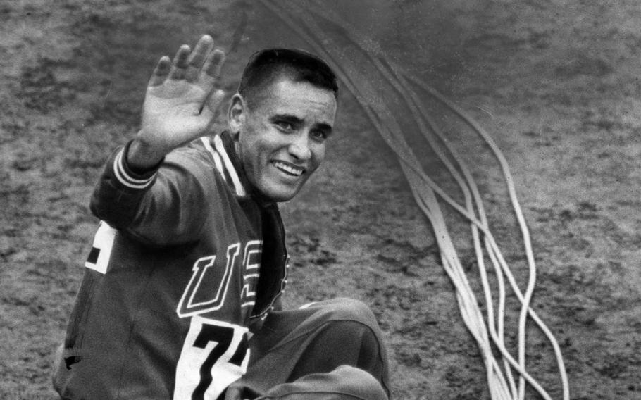 Billy Mills, a U.S. Marine, waves after winning Olympic gold in the 10,000-meter event at the Tokyo Olympics in 1964. Mills won a dramatic, elbow-jabbing, traffic-jam stretch run, beating out Mohammed Gamoudi of Tunesia, who got silver, and world record holder and favorite Ron Clarke of Australia, who captured the bronze.