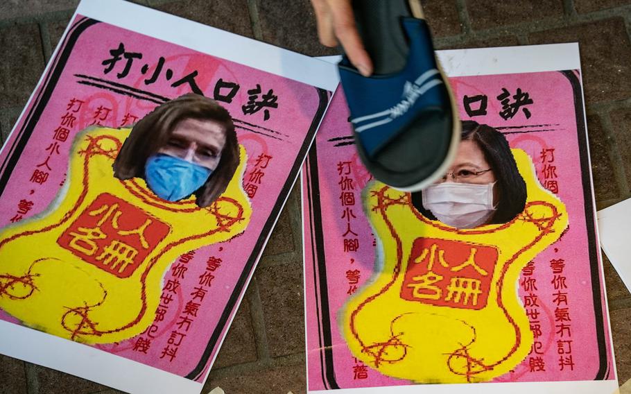A pro-China supporter hits images of U.S. House of Representatives Speaker Nancy Pelosi and Taiwan President Tsai Ing-wen with a shoe, as she carries out a villain hitting ritual during a rally on Aug. 11, 2022, in Hong Kong.