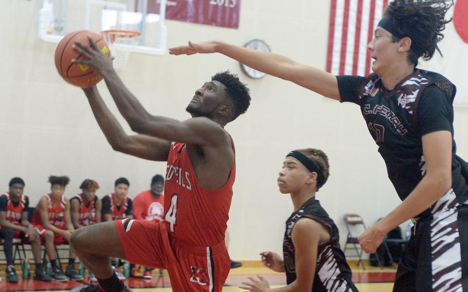 Nile C. Kinnick's Kennedy Hamilton drives to the basket against Matthew C. Perry's Sam Kasperski during Saturday's DODEA-Japan boys basketball game. The Red Devils won 79-67.