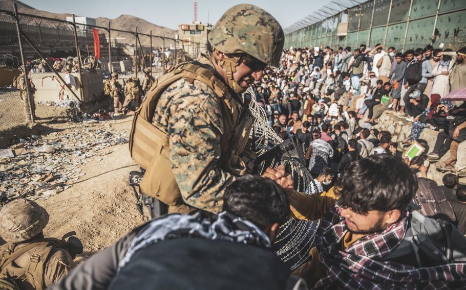 A U.S. Marine assists an Afghan at Hamid Karzai International Airport in Kabul on Aug. 26. The airlift evacuation, which took just over two weeks, saved more than 124,000 people.