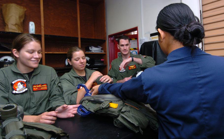 A sailor issues flight gear to other sailors