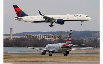 An American Airlines aircraft taxis as a Delta Air Lines aircraft lands at Reagan National Airport in Arlington, Va., on Jan. 24, 2022.