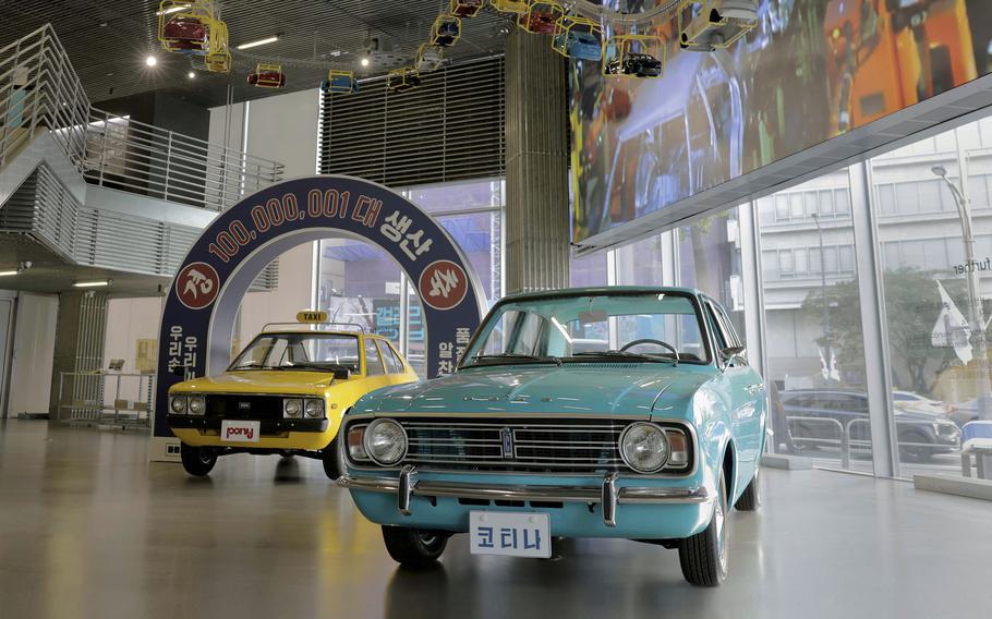 A blue car sits on a museum’s showroom floor.