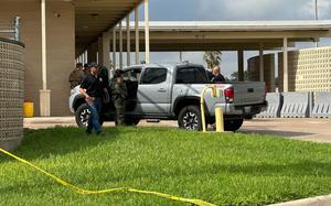 Police tape is strung along the ground, with agents at the scene behind it.