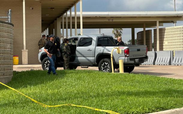 Police tape is strung along the ground, with agents at the scene behind it.