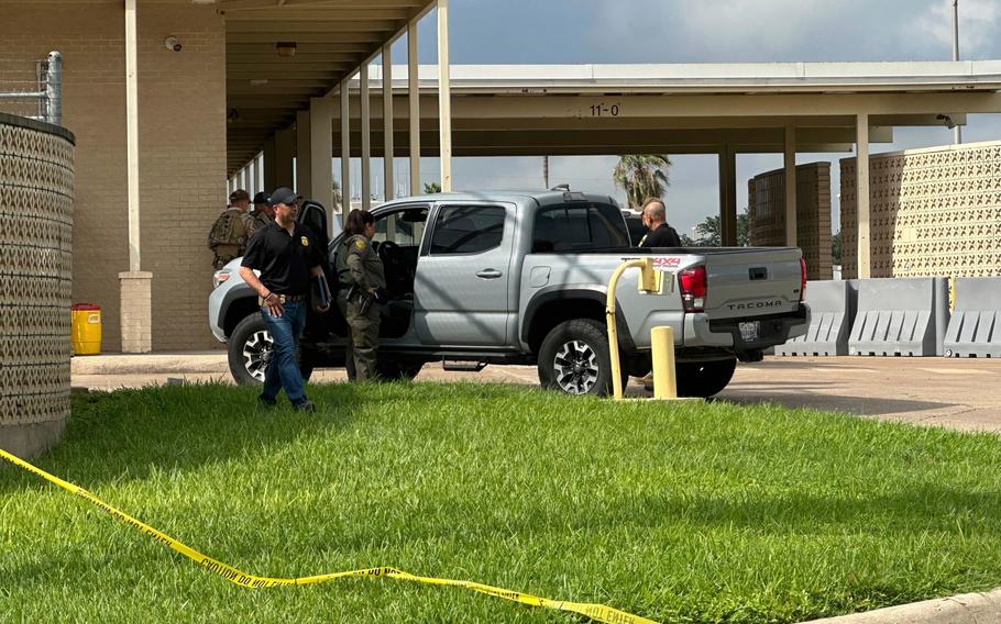 Police tape is strung along the ground, with agents at the scene behind it.