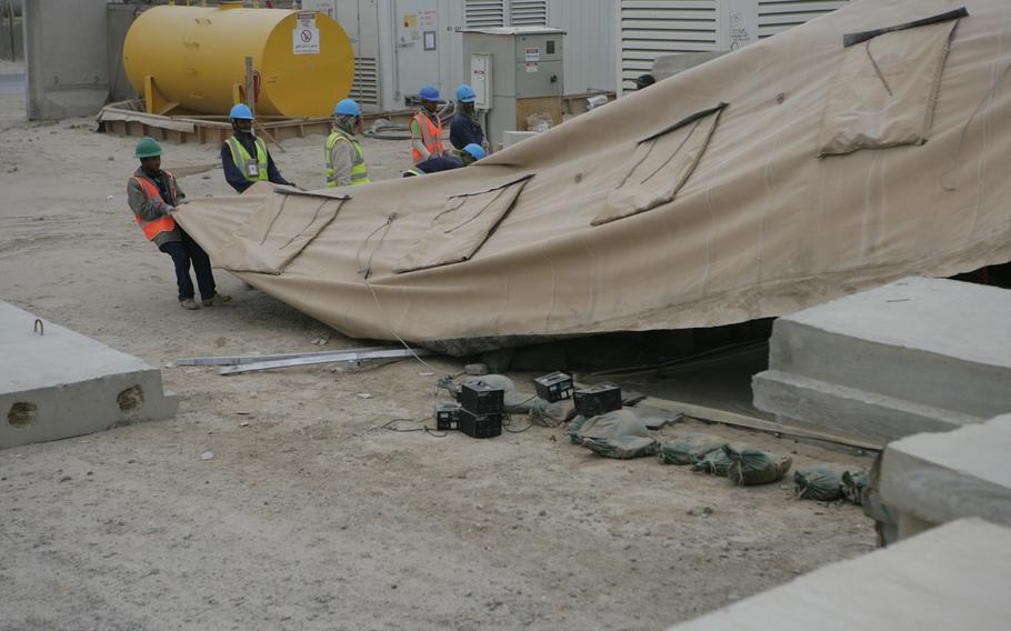 Kellogg, Brown & Root subcontractors tear down the outer lining of a transient tent at Camp Fallujah, Iraq, Nov. 20, 2008. KBR agreed to settle a federal lawsuit alleging that its employees took kickbacks while performing work for U.S. forces in the Middle East, the Justice Department said on June 14, 2022.  