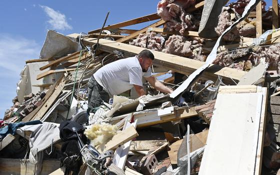 A man climbs on the big pile of rubble that used to be his home.