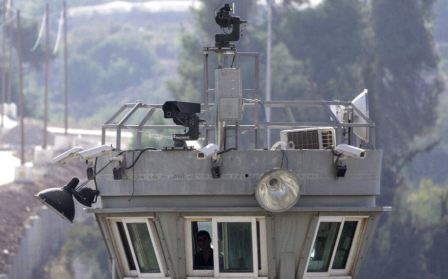 Two robotic guns sit atop a guard tower bristling with surveillance cameras pointed at the Aroub refugee camp in the West Bank, on Oct. 6, 2022.