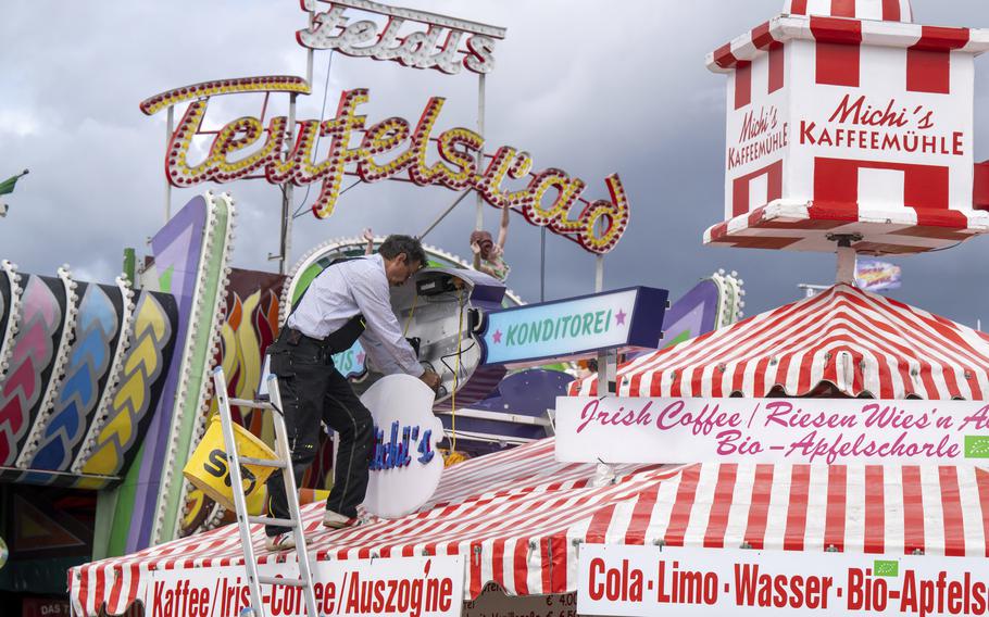A man mounts a light advertisement Sept. 15 on a booth on the Oktoberfest grounds in Munich, Germany. The Oktoberfest is on tap again in Germany after a two-year pandemic interruption. But brewers and visitors are under pressure from inflation in ways they could hardly imagine in 2019. 
