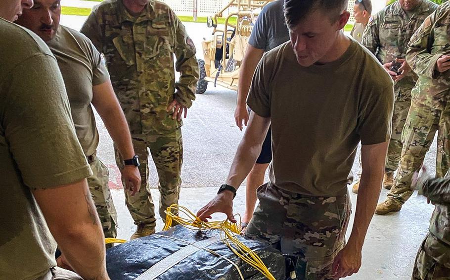 Service members at Andersen Air Force Base, Guam, build an apparatus for dropping medical supplies to a critically injured soldier aboard a vessel at sea, July 25, 2021.