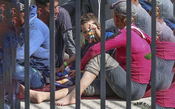 Cuban migrants sit on the floor while waiting to be processed. A little boy, who appears to be less than five, plays with a basketball toy figure. On Wednesday, January 4, 2023 about 40 men, women and some small children entered the next stage in their migration from Cuba to the United States Wednesday when they were processed by the Border Patrol at the agency’s station in the Middle Florida Keys city of Marathon. They were among hundreds of people from Cuba, and one large group of over 100 men and women from Haiti, who’ve landed across the island chain since the end of last week.