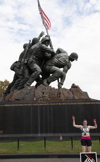 A runner poses in front of the Marine Corps War Memorial after finishing the 48th Marine Corps Marathon on Sunday, Oct. 29, 2023, in Arlington, Va.